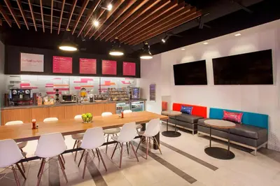 a restaurant with a large wooden table and chairs at Aloft Miami Dadeland in Kendall