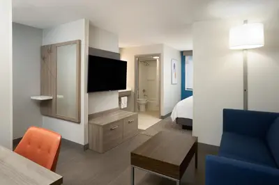 a living room with a room with a bed and a television at Holiday Inn Express Hotel & Suites Kendall East-Miami by IHG in Kendall