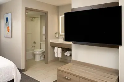 a bathroom with a large flat screen tv on a wall at Holiday Inn Express Hotel & Suites Kendall East-Miami by IHG in Kendall