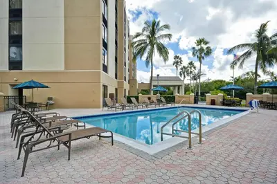 a pool at a hotel with chairs and umbrellas at Hyatt Place Miami Airport-West/Doral in Miami