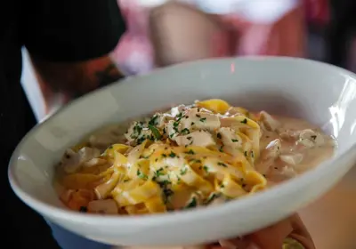 a person holding a bowl of food with pasta at Ocean Reef Suites in Miami Beach