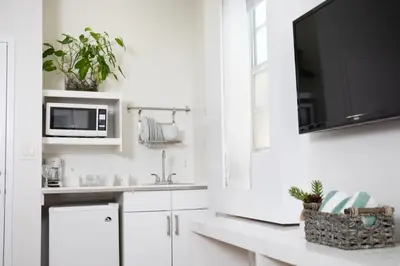 a kitchen with white cabinets and a tv on the wall at Riviere South Beach Hotel in Miami Beach