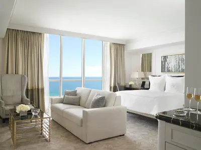 a white bedroom with a bed and a couch and a table at Acqualina Resort and Residences in Miami Beach