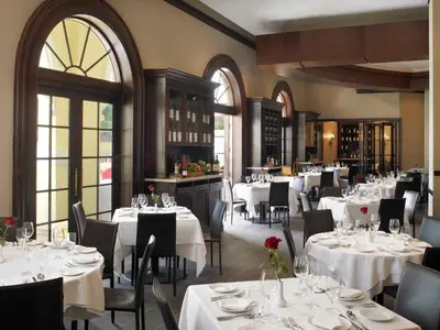 a restaurant with white tables and chairs and windows at Acqualina Resort and Residences in Miami Beach