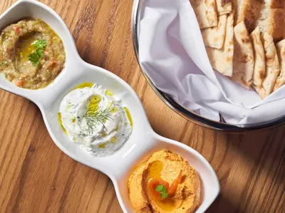 a table with two dishes of dip and a sandwich at Acqualina Resort and Residences in Miami Beach