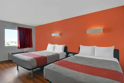 a hotel room with two beds and an orange wall at Motel 6-Cutler Bay, FL in Cutler Bay
