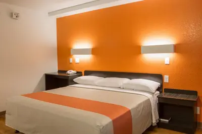 a bedroom with a large bed with an orange wall at Motel 6-Cutler Bay, FL in Cutler Bay