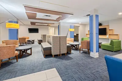 a waiting room with chairs and tables at Holiday Inn Express Ft Lauderdale Cruise-Airport by IHG in Fort Lauderdale