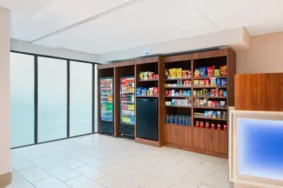 a store aisle with a refrigerator and shelves of food at Holiday Inn Express Ft Lauderdale Cruise-Airport by IHG in Fort Lauderdale
