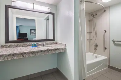 a bathroom with a sink and a tub and a mirror at Holiday Inn Express Hotel & Suites Ft. Lauderdale-Plantation by IHG in Plantation