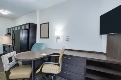 a room with a desk and chairs in a room at Candlewood Suites Fort Lauderdale Airport-Cruise by IHG in Fort Lauderdale