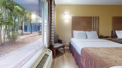 a hotel room with a bed and a window at Rodeway Inn & Suites Fort Lauderdale Airport & Cruise Port in Fort Lauderdale