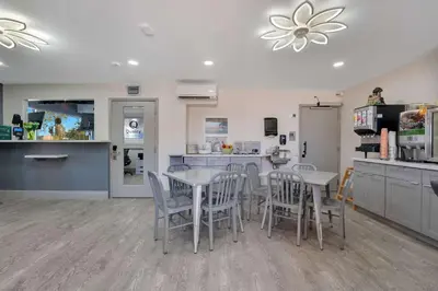a dining room with tables and chairs and a kitchen at Quality Inn & Suites Airport-Cruise Port Hollywood in Hollywood