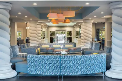 a lobby with blue chairs and tables and columns at Holiday Inn Fort Lauderdale Airport by IHG in Hollywood