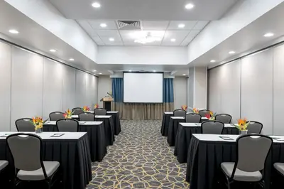 a conference room with tables and chairs and a screen at Holiday Inn Fort Lauderdale Airport by IHG in Hollywood