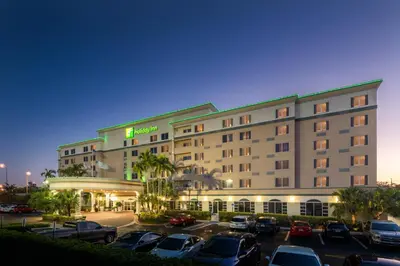 a hotel with cars parked in a parking lot at Holiday Inn Fort Lauderdale Airport by IHG in Hollywood