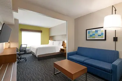 a hotel room with a bed and a blue couch at Holiday Inn Express & Suites Pembroke Pines-Sheridan St by IHG in Pembroke Pines