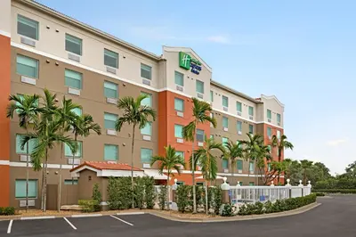 a hotel with palm trees in a parking lot at Holiday Inn Express & Suites Pembroke Pines-Sheridan St by IHG in Pembroke Pines