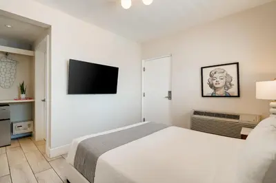 a white bedroom with a bed and a flat screen tv at Waterside Hotel and Suites in Miami Beach