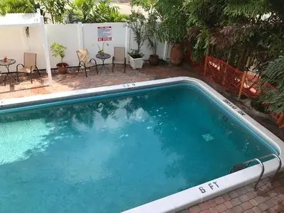 a large swimming pool sitting next to a patio at The Big Coconut Guesthouse - Gay Men's Resort in Fort Lauderdale