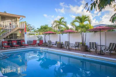 a pool at a hotel with chairs and umbrellas at The Big Coconut Guesthouse - Gay Men's Resort in Fort Lauderdale