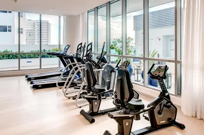 a gym with several treadmills and elliptical machines at Global Luxury Suites at Monte Carlo in Miami Beach