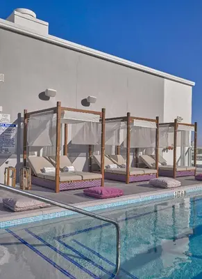 a row of beds next to a swimming pool at ABAE Hotel by Eskape Collection in Miami Beach