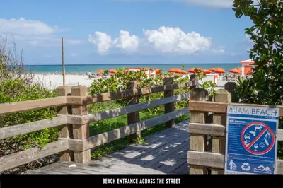 a wooden fence next to a beach with umbrellas at Suite Love in Miami Beach