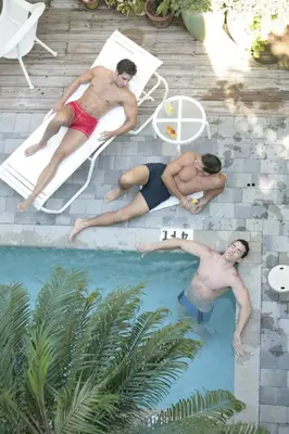 two men are laying in a swimming pool at Pineapple Point Guesthouse & Resort - Gay Men's Resort in Fort Lauderdale
