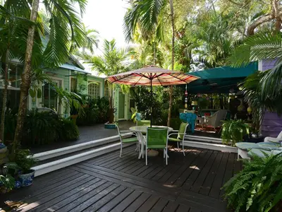 a wooden deck with a table and chairs and an umbrella at Pineapple Point Guesthouse & Resort - Gay Men's Resort in Fort Lauderdale