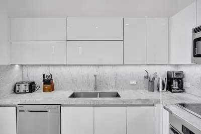 a white kitchen with white cabinets and a sink at Modern Penthouse condo with 2 Large private terraces in Hollywood