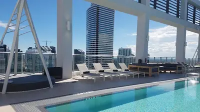 a pool on the roof of a building with chairs at Downtown Miami Deluxe Apartment in Miami