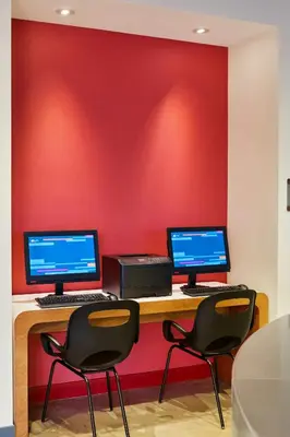 two computers sitting on a desk in front of a red wall at Aloft Miami Airport in Miami
