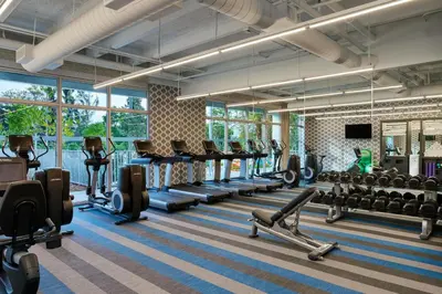 a gym with rows of exercise equipment and windows at Aloft Miami Airport in Miami