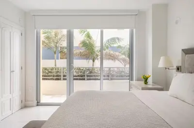 a white bedroom with a bed and a large window at Beachfront Bentley Hotel One Bedroom Suite with Balcony and Beach access in Miami Beach