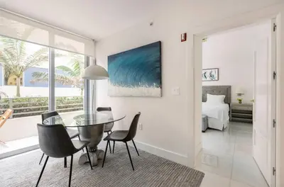 a dining room with a glass table and chairs and a bed at Beachfront Bentley Hotel One Bedroom Suite with Balcony and Beach access in Miami Beach
