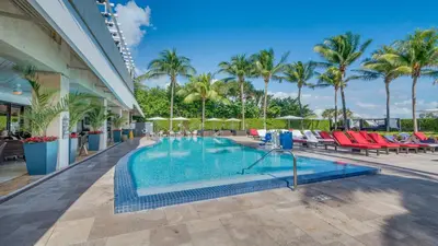 a pool at a resort with chairs and palm trees at Beachfront Bentley Hotel One Bedroom Suite with Balcony and Beach access in Miami Beach