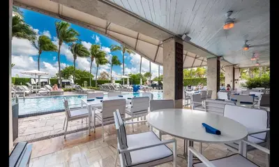 a patio with a table and chairs and a pool at Beachfront Bentley Hotel One Bedroom Suite with Balcony and Beach access in Miami Beach