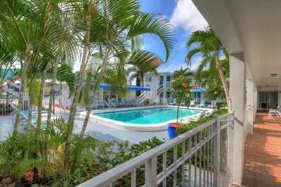 a balcony view of a swimming pool with palm trees at May-Dee Suites in Florida in Hollywood