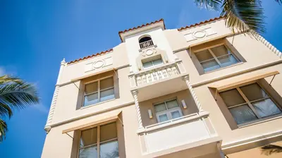 a white building with windows and a palm tree at Casa Boutique Hotel in Miami Beach