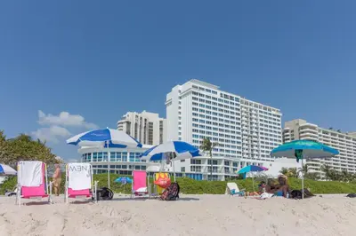 a group of people sitting on a beach with umbrellas at Castle Beach: Rumba Suite in Miami Beach