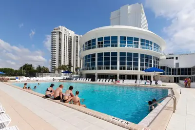 a group of people sitting in a swimming pool in front of a building at Castle Beach: Rumba Suite in Miami Beach