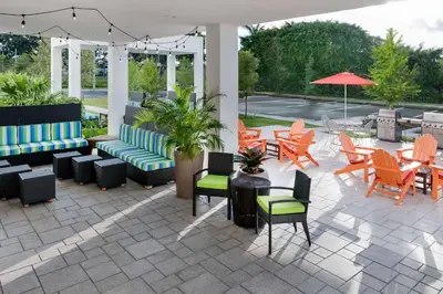 a patio with chairs and tables and an umbrella at Home2 Suites By Hilton Ft. Lauderdale Airport-Cruise Port in Dania Beach