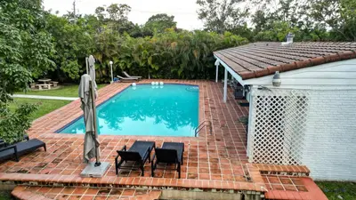 a swimming pool with two chairs and a house at La Finca in Miami