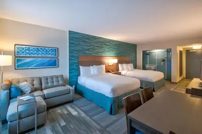 a hotel room with two beds and a couch at TownePlace Suites by Marriott Miami Airport in Miami