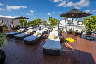 a deck with a bunch of couches and an umbrella at Riviera Suites in Miami Beach