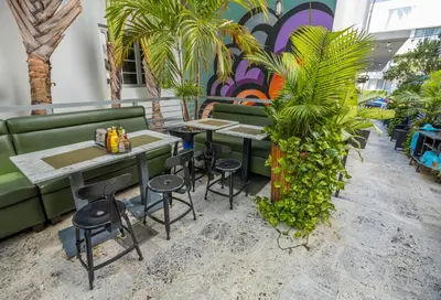 a restaurant with green chairs and tables and plants at Riviera Suites in Miami Beach