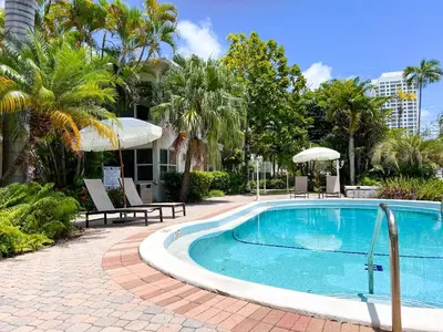 a swimming pool with two chairs and an umbrella at Winterset in Fort Lauderdale