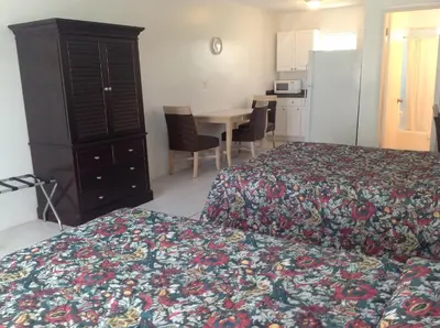 a bedroom with a bed and a table and a kitchen at Birch Patio Motel in Fort Lauderdale