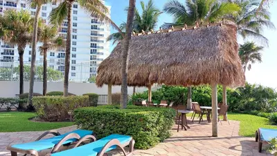 a straw hut with chairs and tables and palm trees at The Tides 1bedroom apt 3rd floor We are on the Beach! in Hollywood